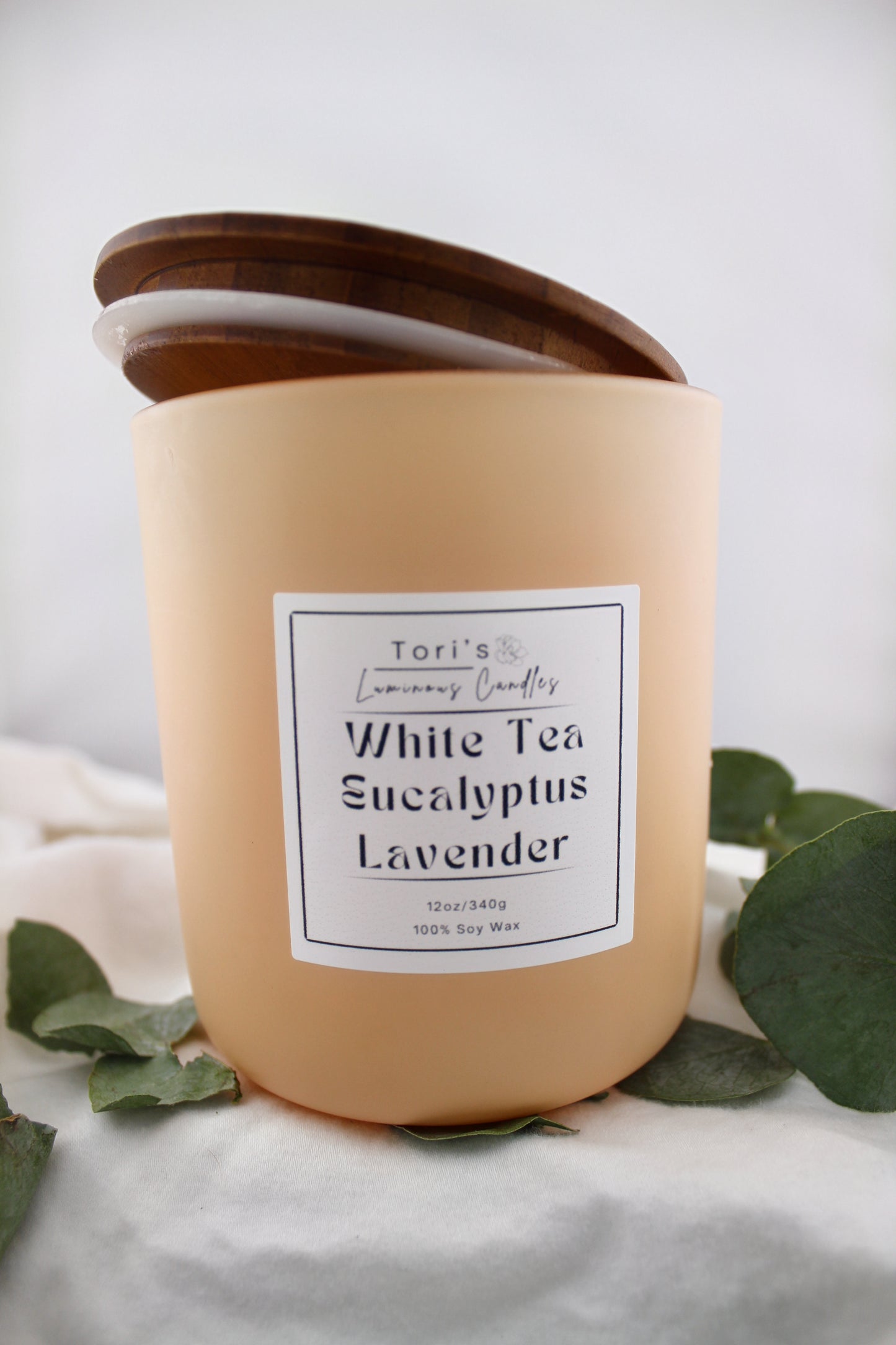 White tea, eucalyptus, and lavender candle in matte sage 8 oz and matte peach 12 oz jars, styled in a peaceful setting with soft lighting—ideal for spa-inspired relaxation at home or in a salon.