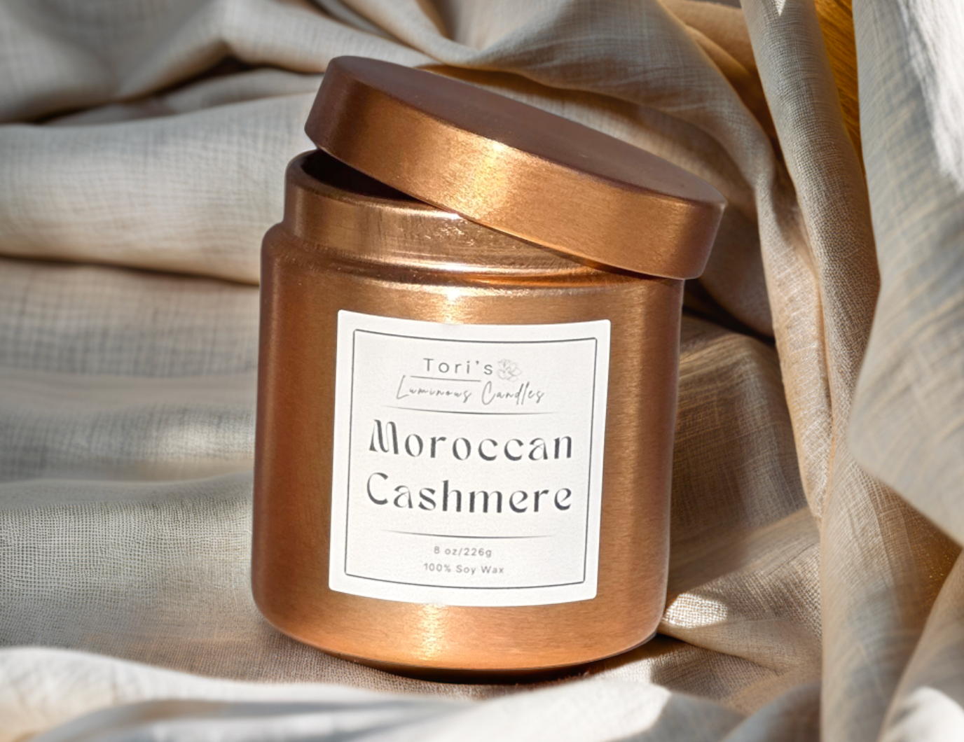 Moroccan Cashmere candle in a 12 oz matte peach jar and 8 oz copper tin, styled in an elegant, minimalist space that reflects the essence of quiet luxury.