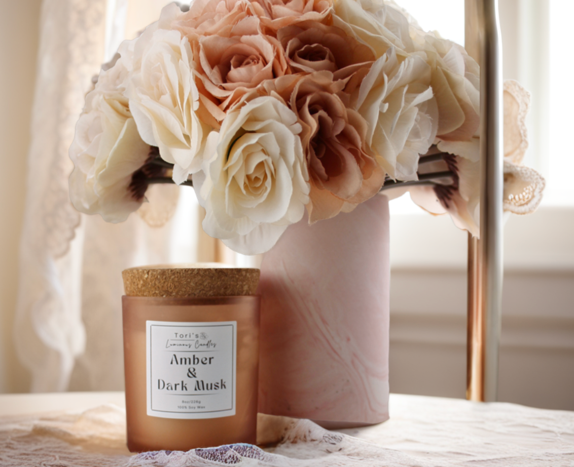 Amber & Dark Musk candle in a frosted amber 8 oz jar and matte cream 12 oz jar, styled on a neutral-toned surface with soft lighting, showcasing the elegant vessels and cozy home décor vibes.