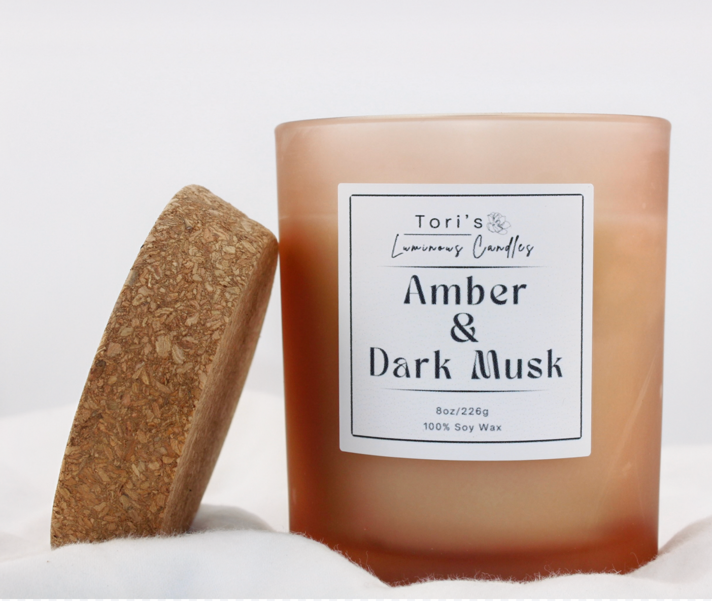 Amber & Dark Musk candle in a frosted amber 8 oz jar and matte cream 12 oz jar, styled on a neutral-toned surface with soft lighting, showcasing the elegant vessels and cozy home décor vibes.