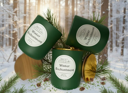 A Winter Enchantment soy candle surrounded by cozy winter accents. The label highlights notes of citrus, pine, pear, juniper, and sage. The scene evokes a snowy forest feeling with a serene, winter wonderland aesthetic.