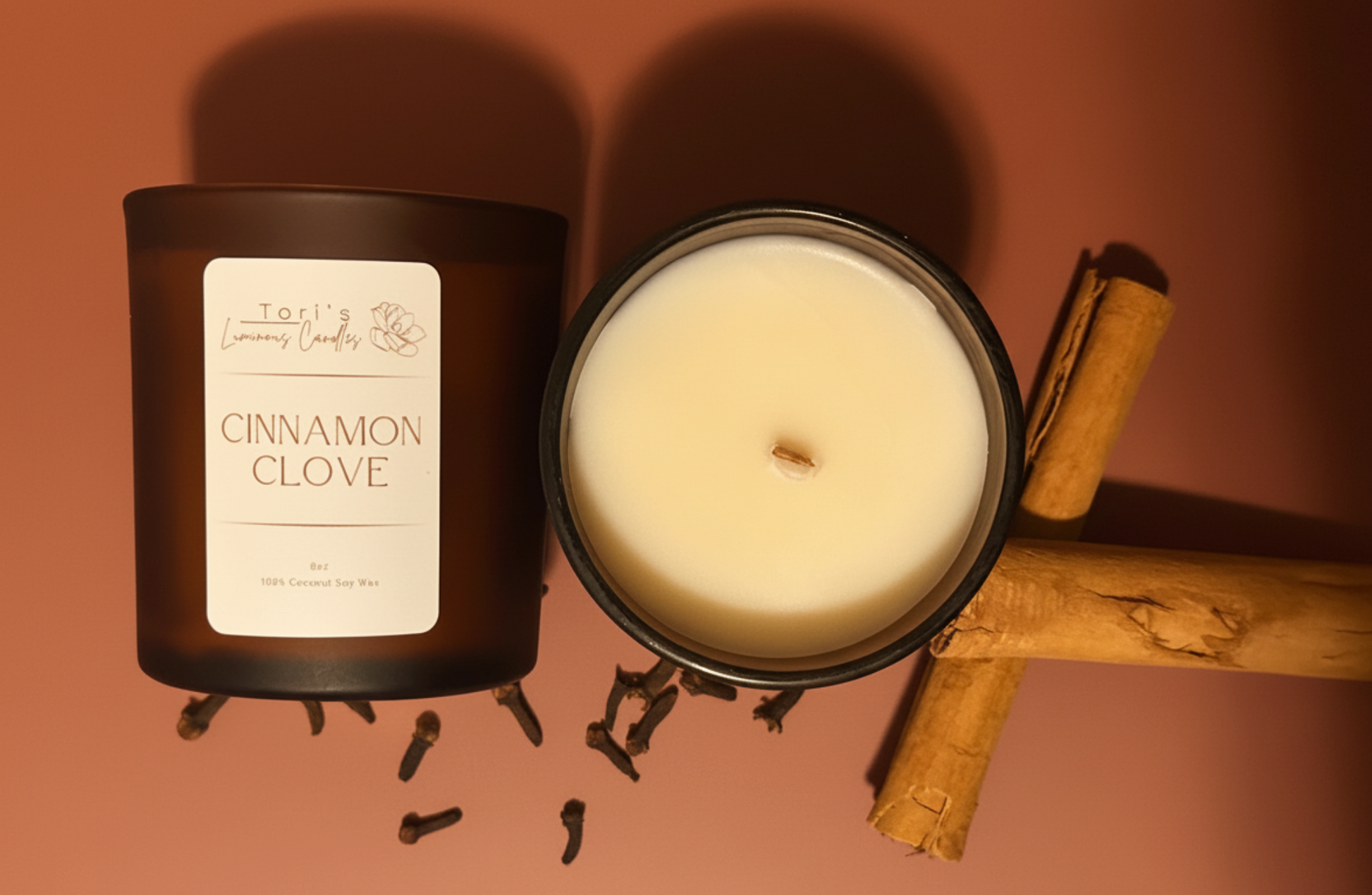 cinnamon and clove soy candle styled with cinnamon sticks, whole cloves, and warm neutral textures, creating a cozy, spiced holiday atmosphere.