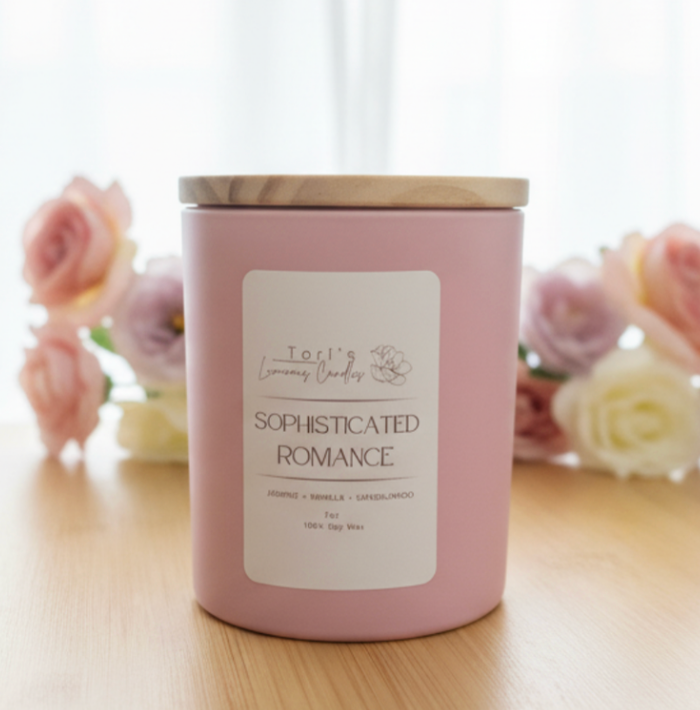 A luxury candle titled 'Sophisticated Romance' in a minimalist glass jar. The label is clean and modern, listing notes of Jasmine, Vanilla, and Sandalwood. The candle is styled on a marble surface next to a sprig of dried jasmine and a sandalwood incense stick.