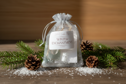 Fragrance bottle in a clear drawstring bag labeled 'Winter Enchantment' on a white background